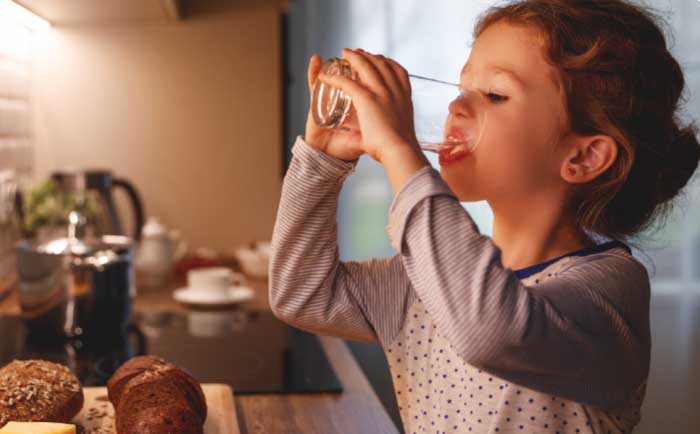 child drinking water from a glass